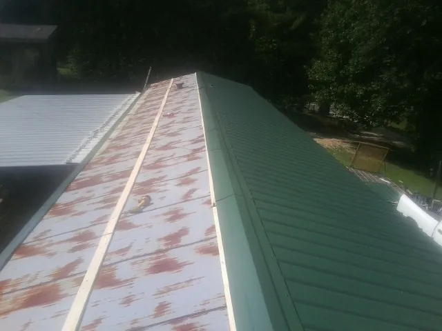 Old rusted panels beside newly installed green metal roofing — Wind Damage Roof Repair by Roofing Brothers in Decherd