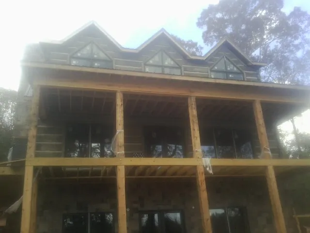 Dormers and porch framing on a large log home under construction — Roof Coating work by our crew in Decherd