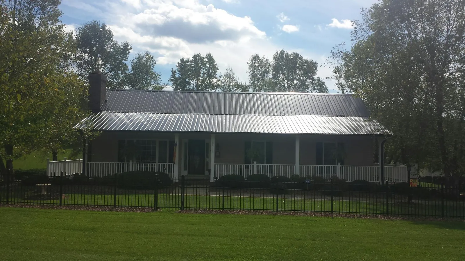 Gray metal roof on a brick ranch with a full width front porch — Gutter Guard Installation work by our crew in Decherd