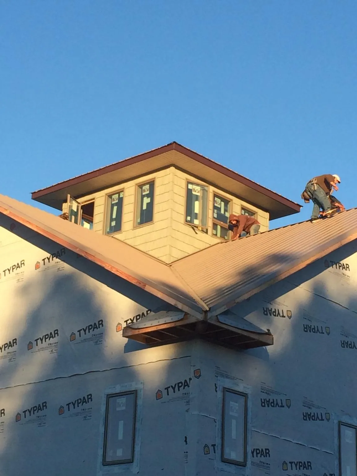 Roofers working around a rooftop cupola on a new metal roof at sunset — Roof Waterproofing in Decherd by Roofing Brothers